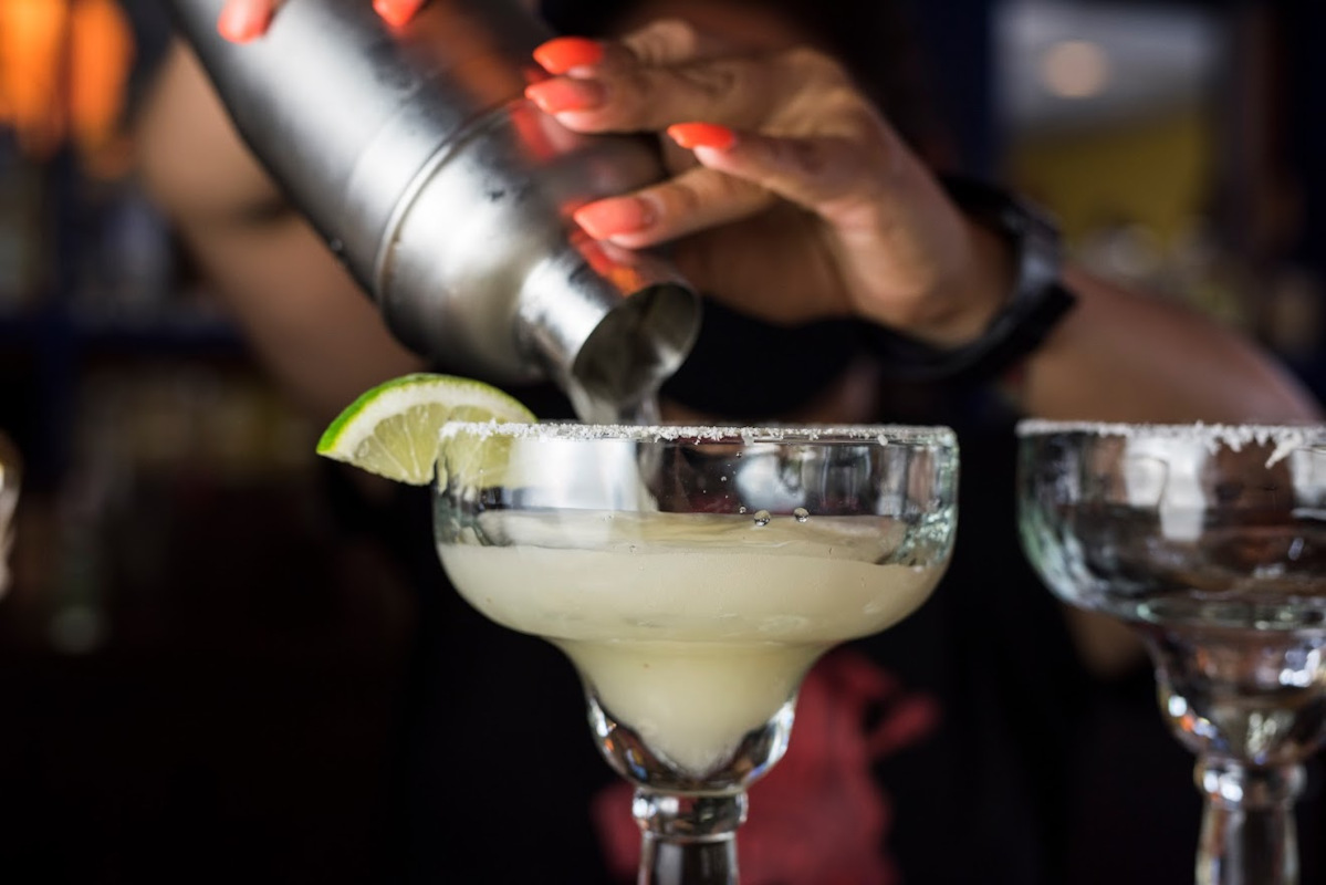 The bartender pours a cocktail in glass